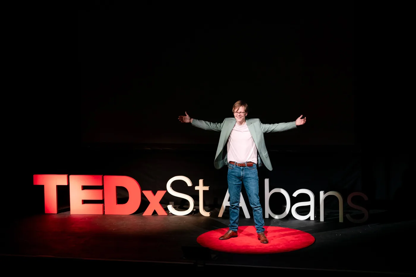Nat Hawley on stage in front of the TEDx St Albans lettering