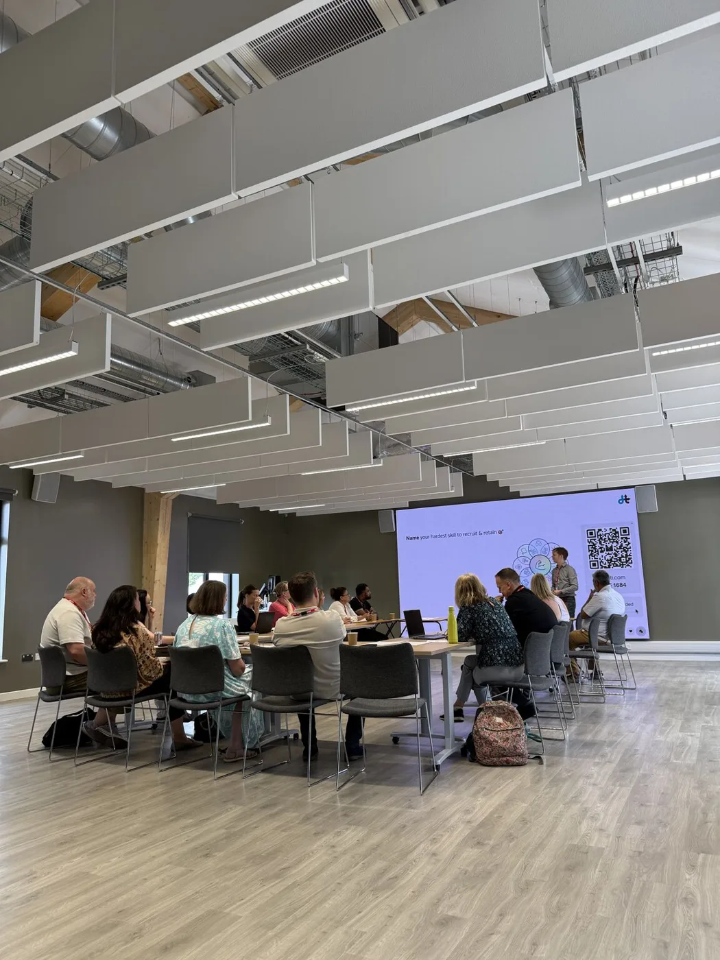 A Divergent Thinking session, with people seated at long tables facing a presentation screen