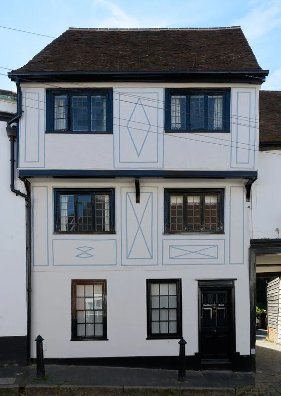A white three storey timber-framed house on Fishpool Street with dark leaded windows and pale blue pargetting patterns on the render